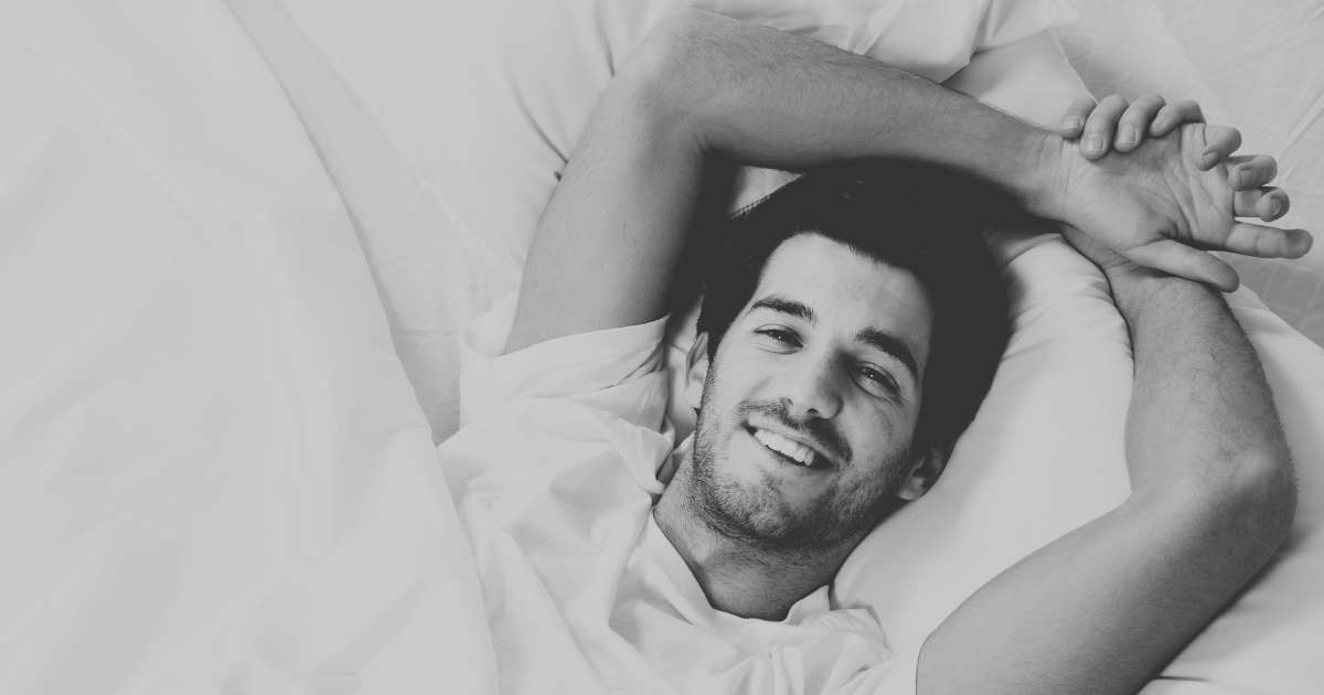 Image of a man lying on the bed, smiling.